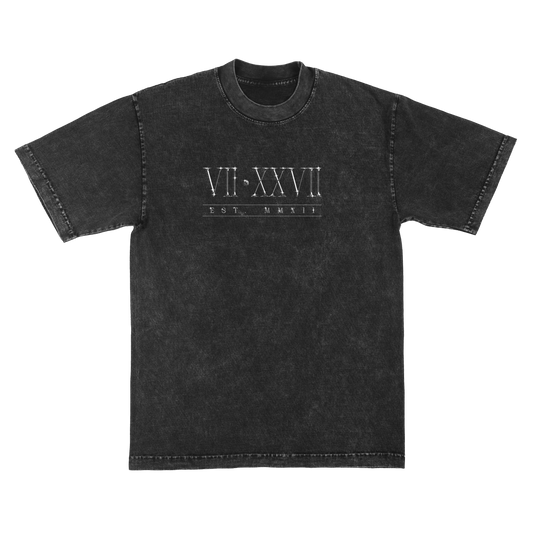 A washed black short-sleeve t-shirt with a white graphic print on the chest featuring Roman numerals 'VII•XXVII' and the text 'EST. MMXII'.